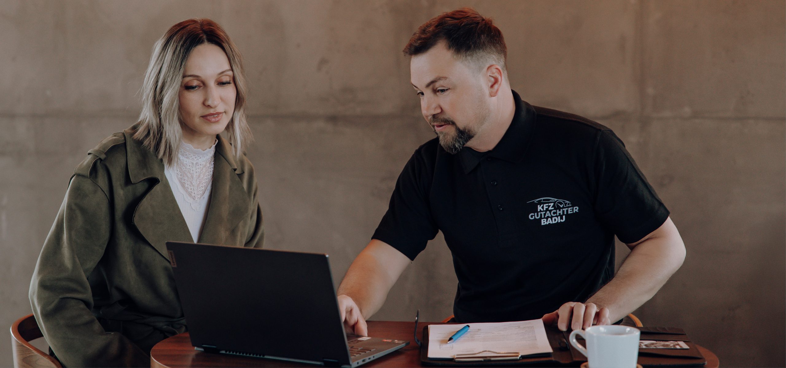 Foto von Viktor Badij mit einer Kundin vor einem Laptop bei der Gutachtenerklärung.