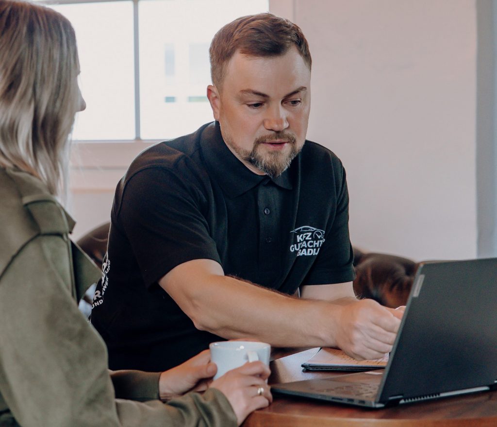 Foto von Viktor Badij mit einer Kundin vor einem Laptop bei der Gutachtenerklärung.