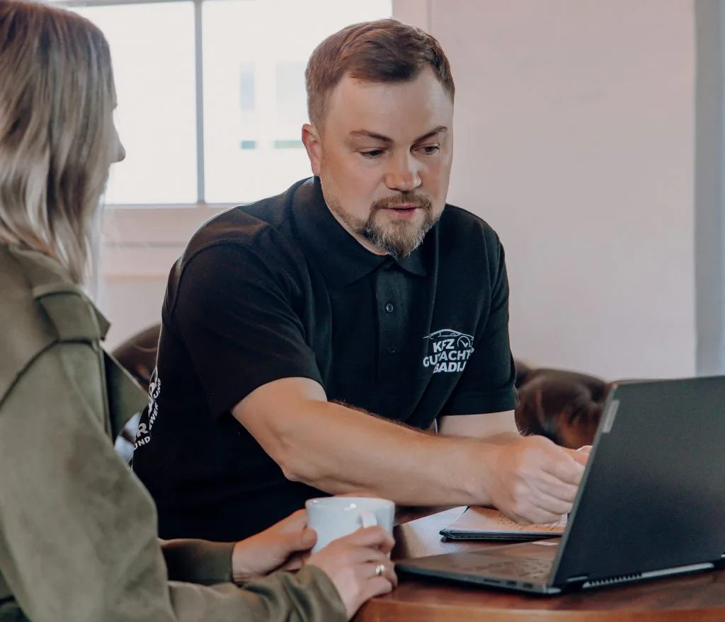 Foto von Viktor Badij mit einer Kundin vor einem Laptop bei der Gutachtenerklärung.